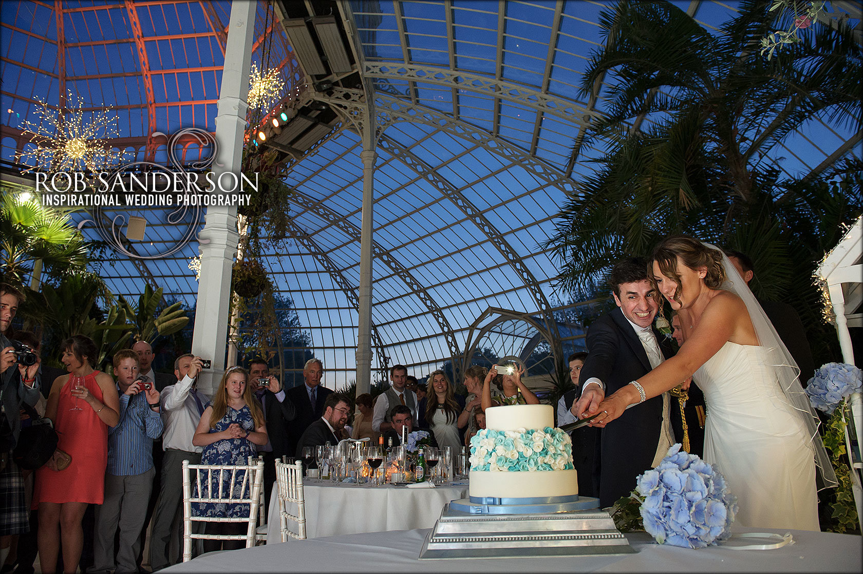 cutting the cake with spectacular view of the Palm House at night in the background